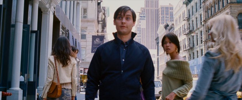 Peter Parker on sidewalk with women staring at him.