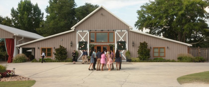 Exterior shot of a wedding venue made from a converted barn with women standing around.