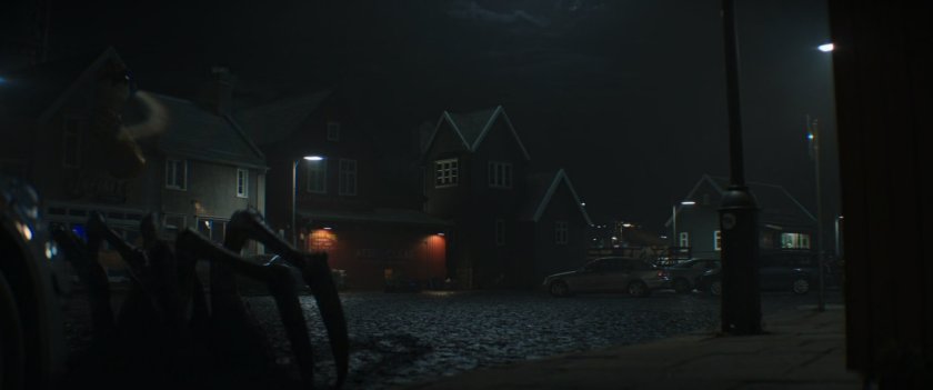 Foggy night time shot of the town of New Asgard with a shadow creature in the foreground.