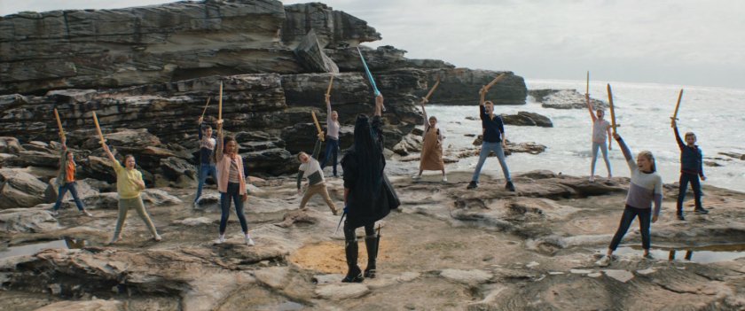 Valkyrie trains many kids on sword handling on the rocks near the ocean.