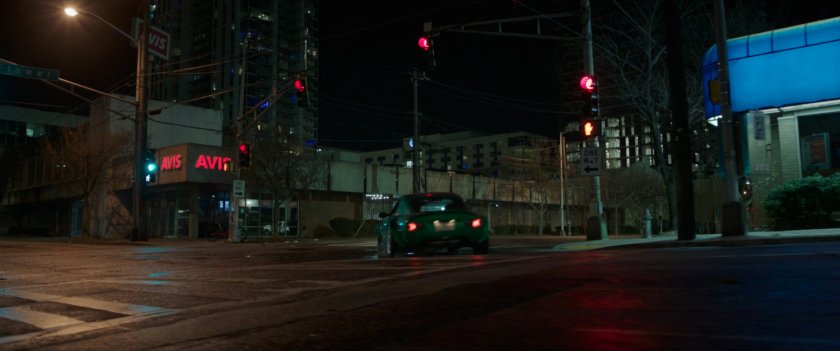 A green car turns a corner onto Flower Street.