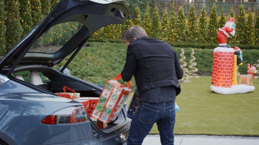 Kevin Bacon getting holiday packages out of a car's trunk.