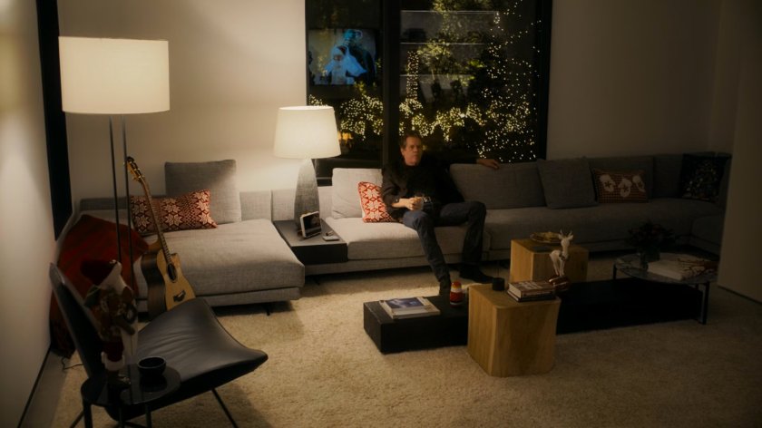 Kevin Bacon watches television on his couch.