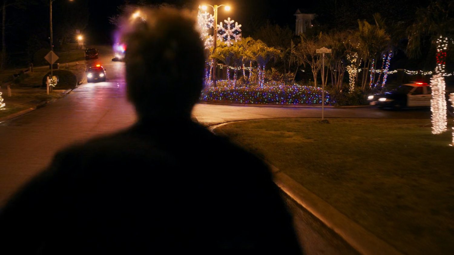 Kevin Bacon runs towards police cars.