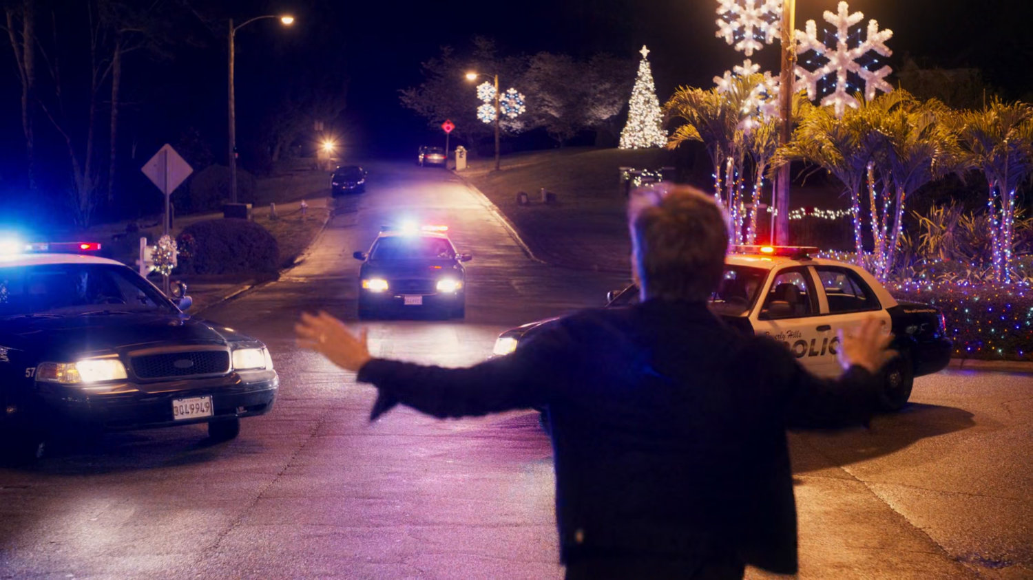 Kevin Bacon runs towards police cars.