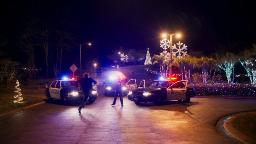 Kevin Bacon runs towards police cars.