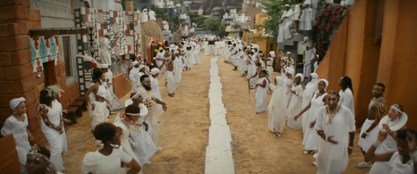 Wakandans gather on a dirt covered city street.