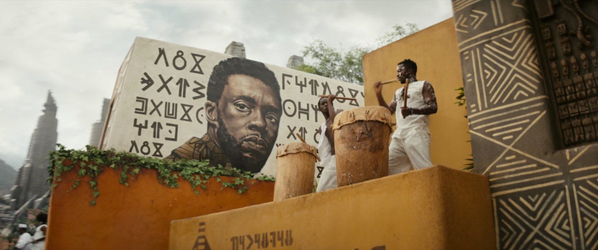 A memorial painting of T'Challa looms over two drummers.