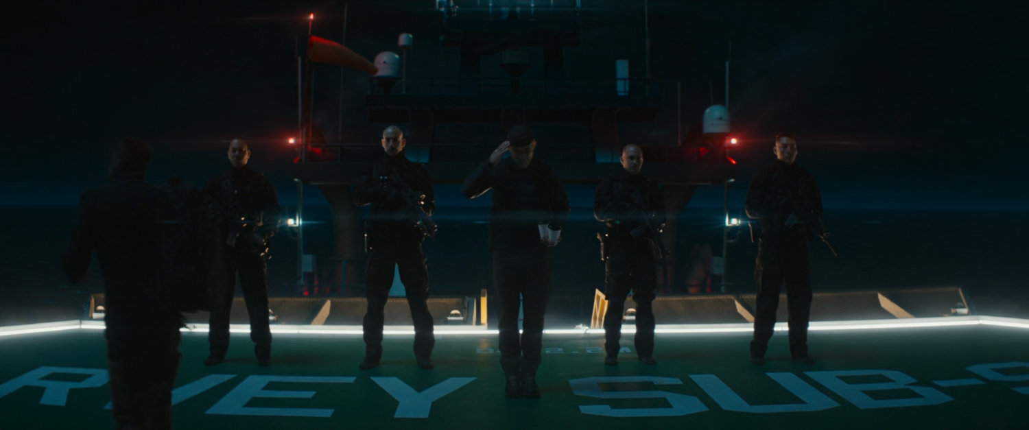 Soldiers stand on the deck of a boat at night.
