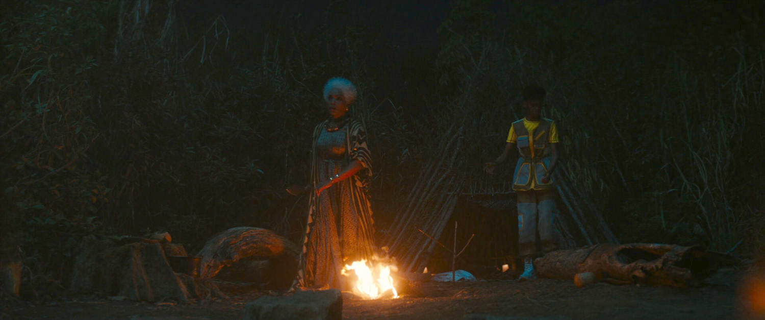 Ramonda and Shuri by a campfire at night.