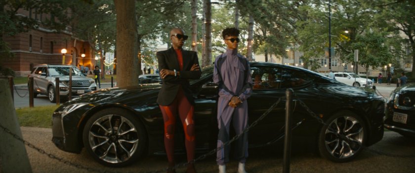Okoye and Shuri stand in front of a car on the MIT campus.