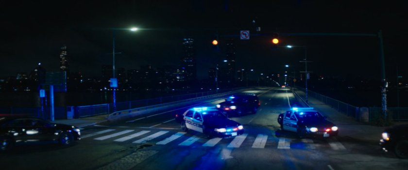 Police cars blockade Boston bridge at night.