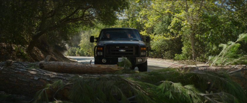 Van stopping on road in front of felled tree.
