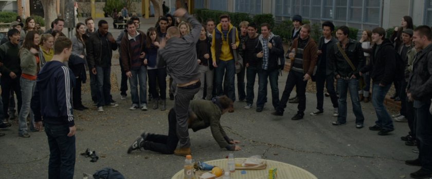 Flash Thompson beats up Peter Parker as other students watch.