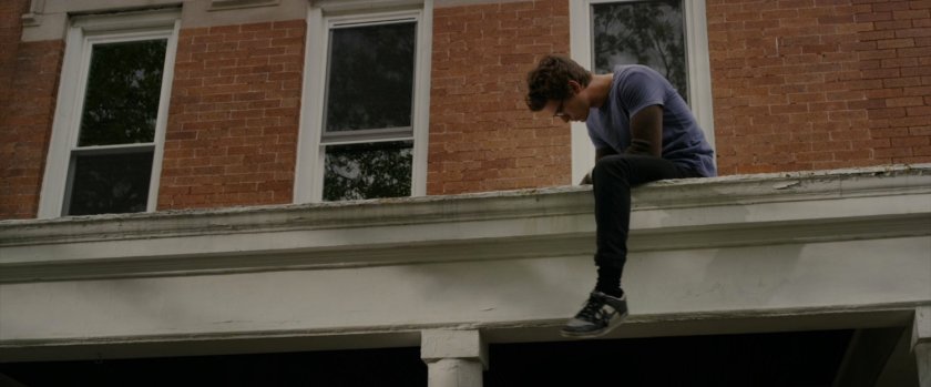 Peter Parker sits on the roof of his house.