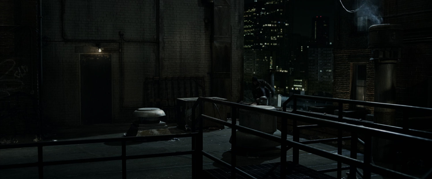 Peter Parker chased across the roof by a thug.