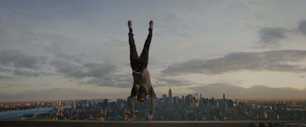 Peter Parker doing a handstand on the roof of a skyscraper.