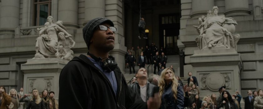 Onlookers outside police plaza watch Spider-Man web a thug.