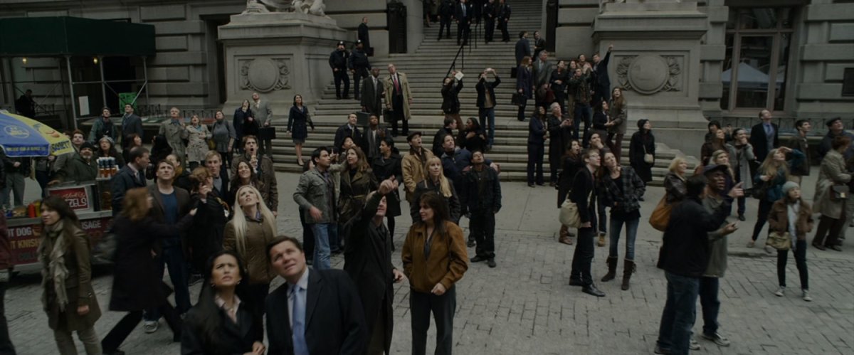 Onlookers outside police plaza watch Spider-Man web a thug.