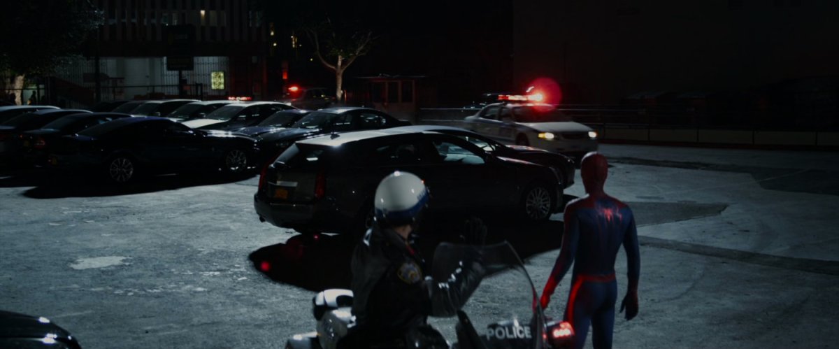 Spider-Man watches more police cars arrive in the parking lot.