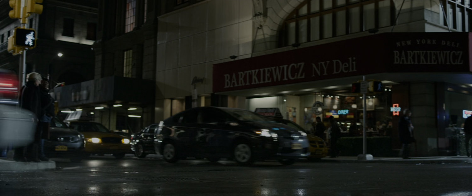 New York street corner at night, showing the Bartkiewicz NY Deli.
