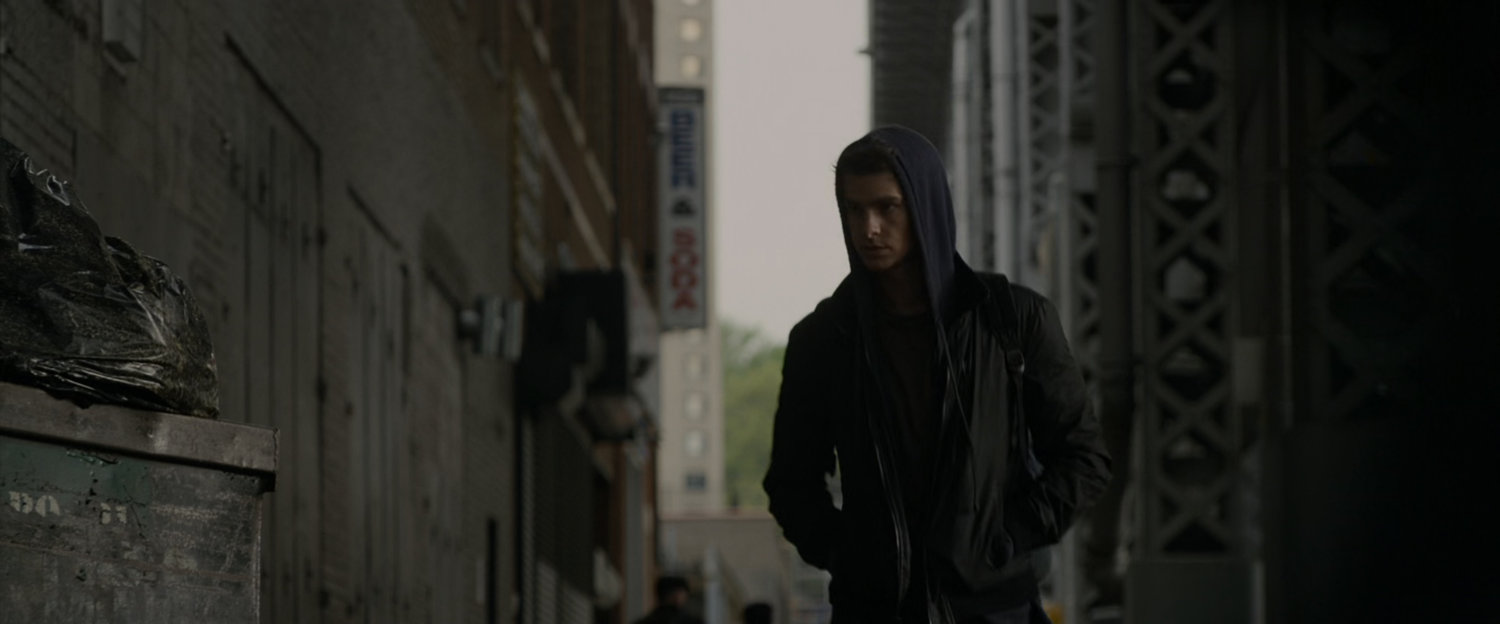 Peter Parker walks down sidewalk.