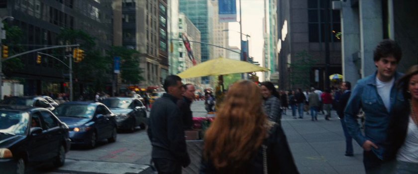 Spider-Man swings past a crowded New York City street.