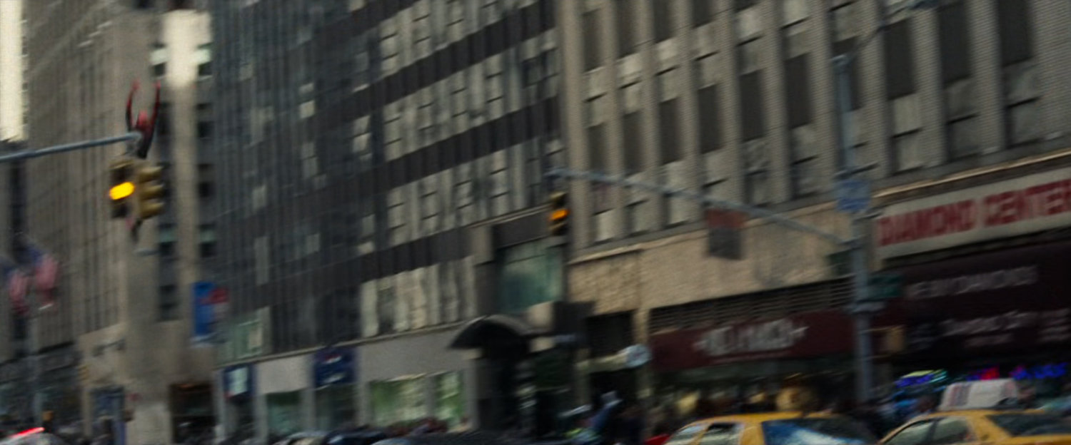 Spider-Man swings past a crowded New York City street.