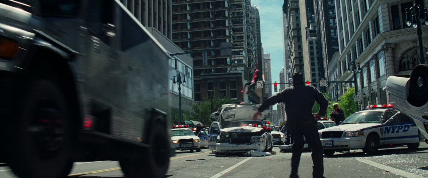 Spider-Man swings towards robber in street.