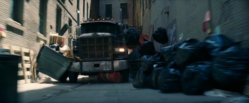 Tow truck driving through alley, hitting dumpsters and trash bags.