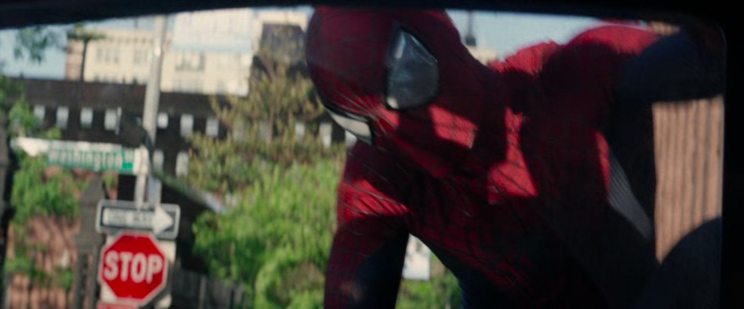 Spider-Man on hood of tow truck looking in window.