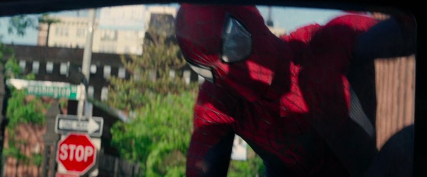 Spider-Man on hood of tow truck looking in window.