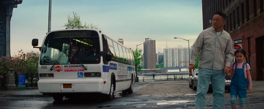 A bus moves past a man and a young girl.