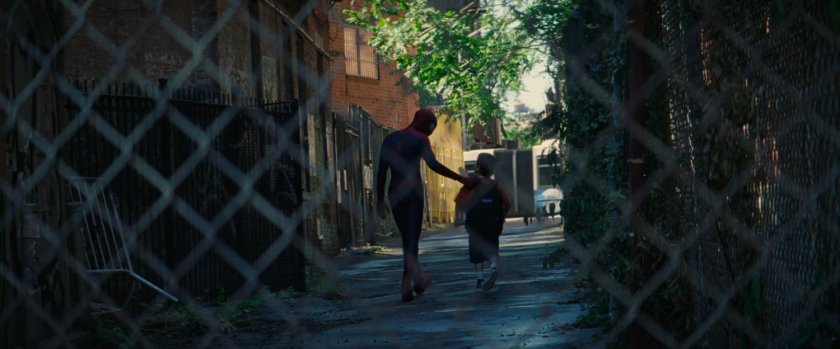 Spider-Man and young boy walk through alley.