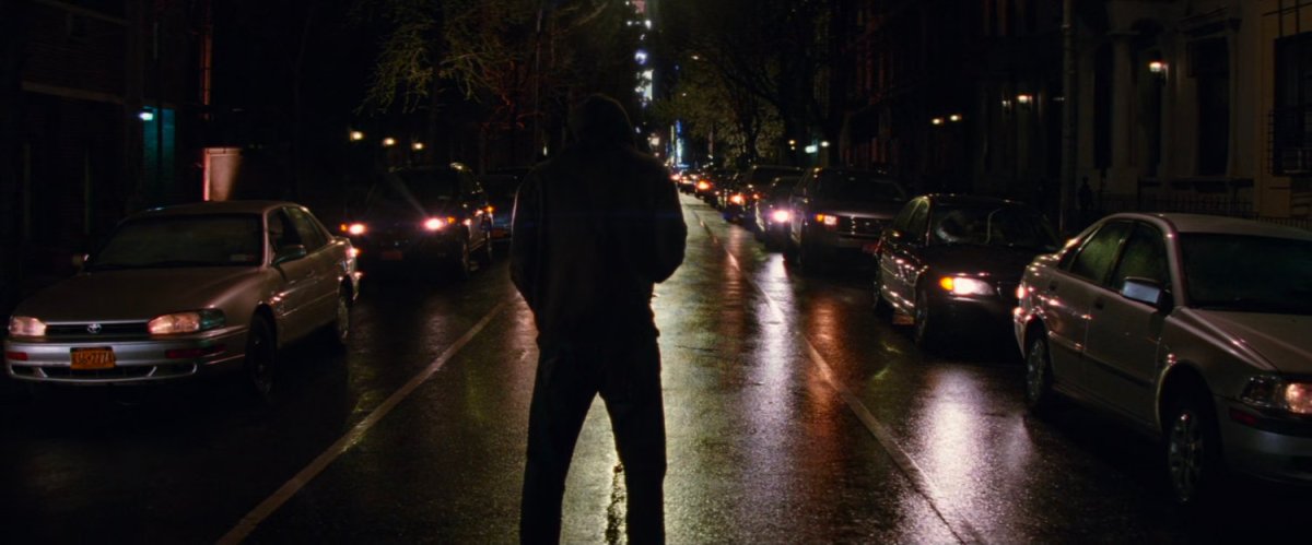 Silhouetted man standing in dark street.
