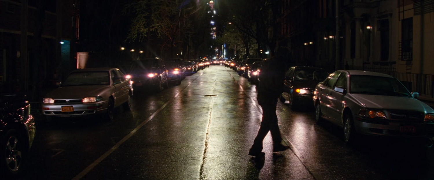 Silhouetted man standing in dark street.