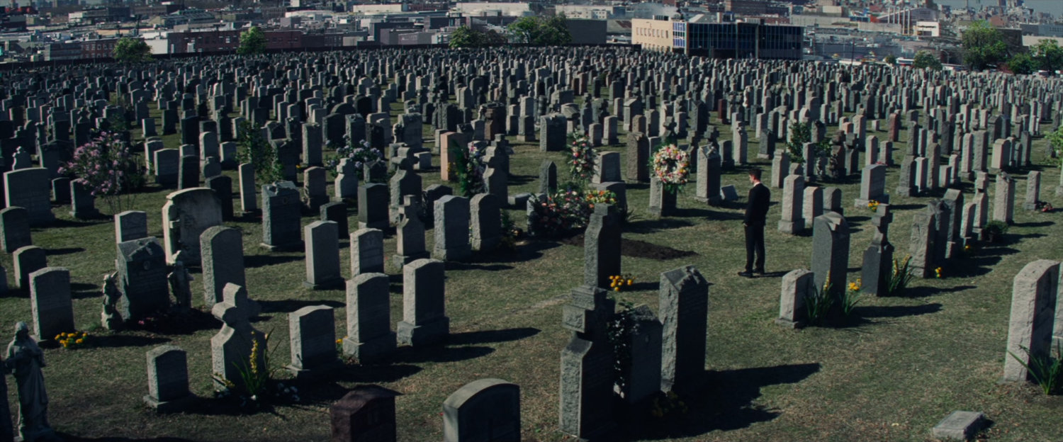 Peter Parker at cemetery with New York in background.