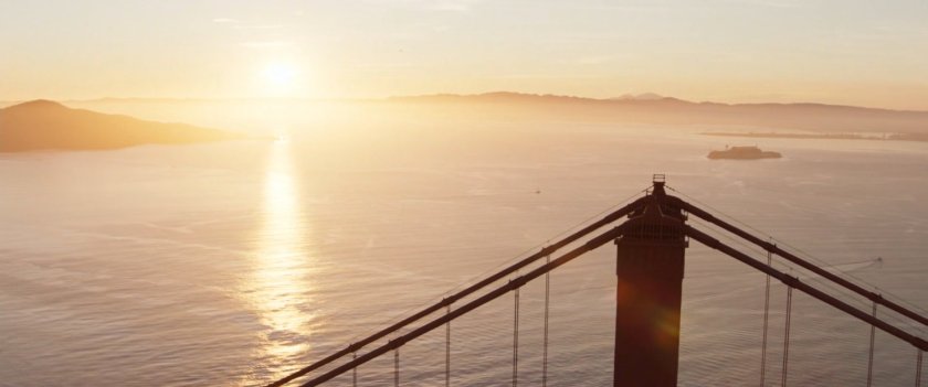 Aerial shot of Golden Gate Bridge and setting sun behind it.