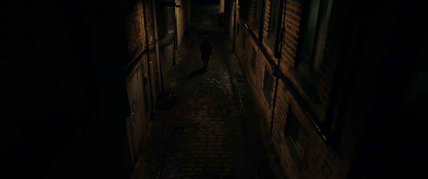 Agent Ross running down a dark alley.