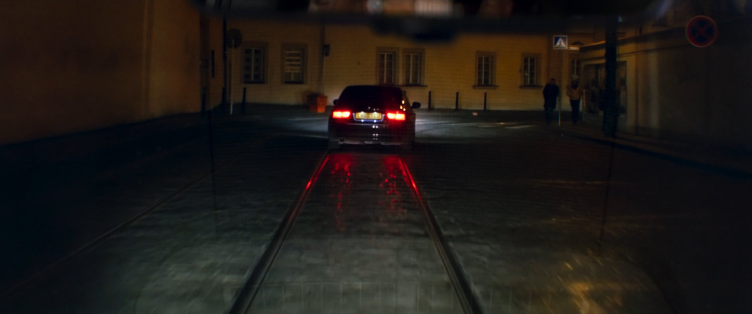 A car driving on a dark cobblestone street.