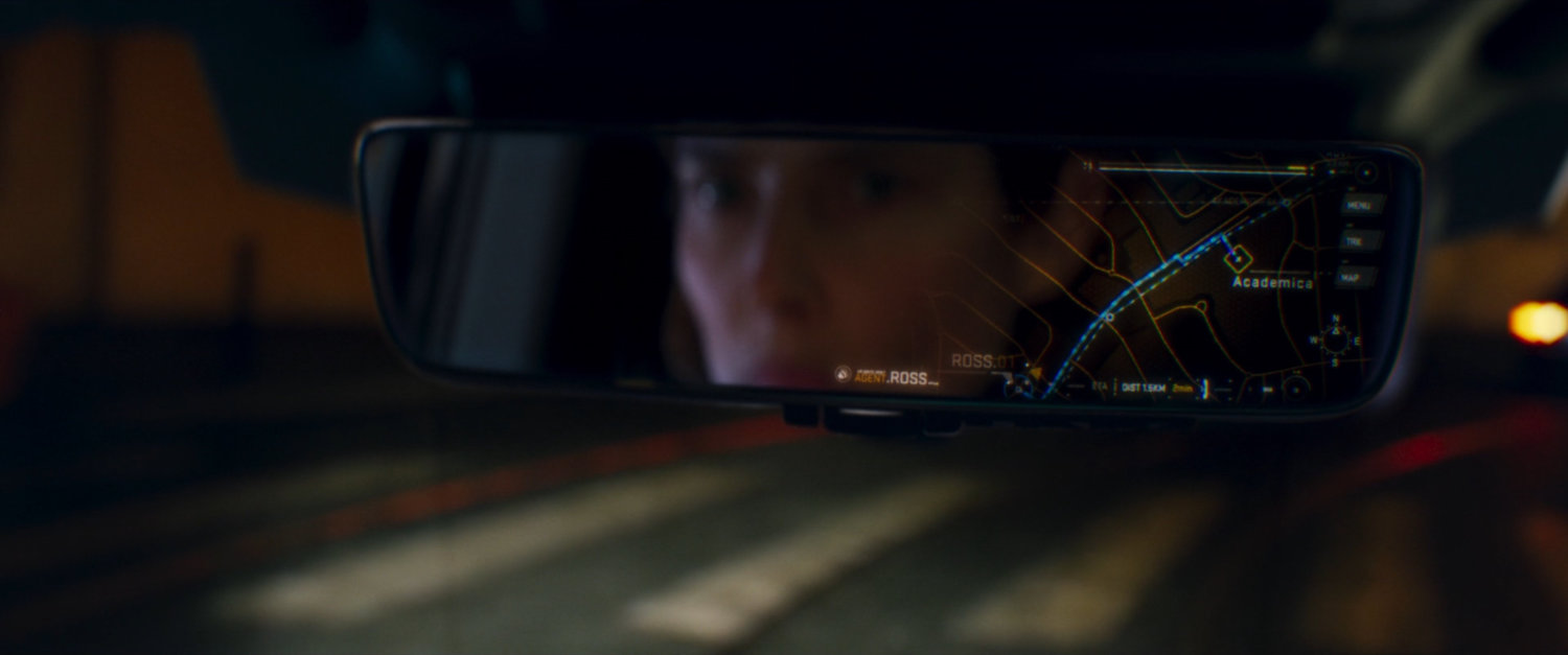 Maria Hill reflected in rearview mirror, which contains a digital map of Agent Ross's location.