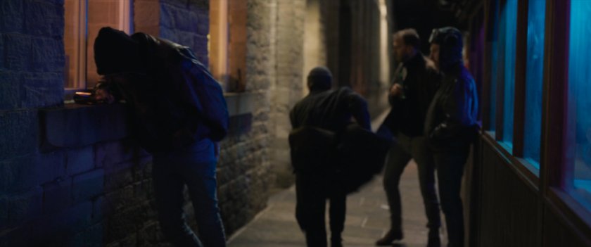 Agent Ross running on sidewalk past onlookers.