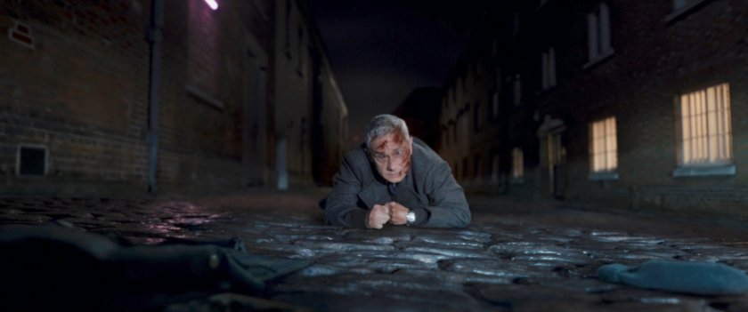 Agent Ross lying on cobblestone road.