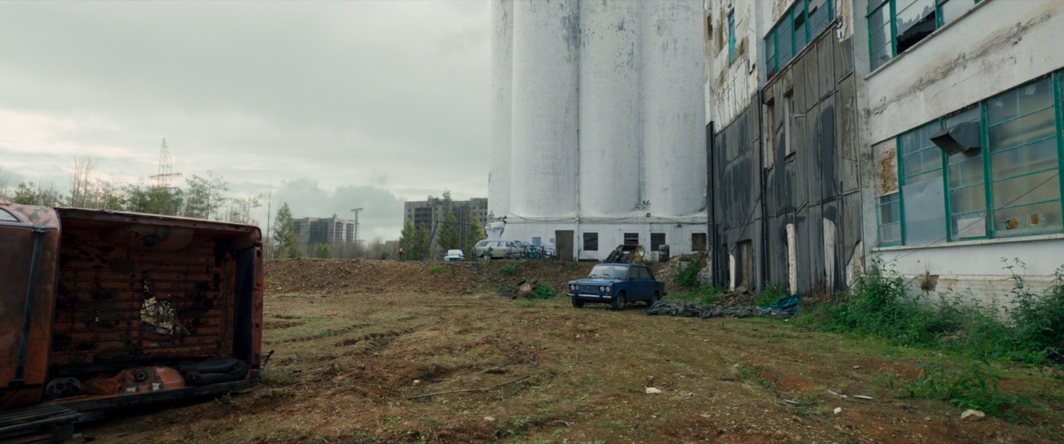 A blue car drives past the exterior of New Skrullos.