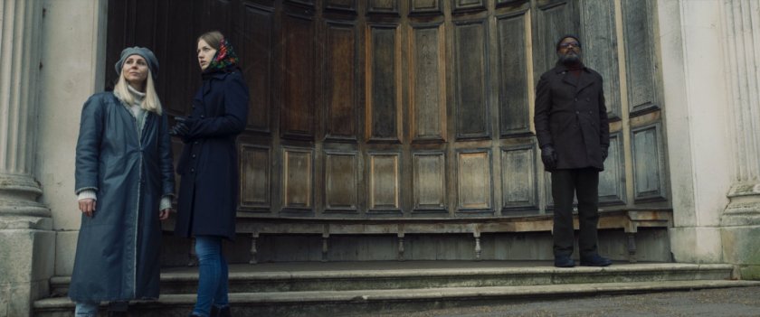 Nick Fury and two civilians standing in an alcove.