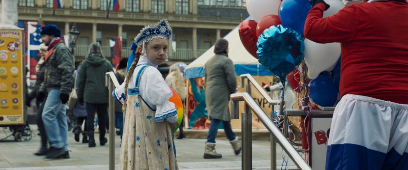 A young girl with rainbow ball in a Russian square.