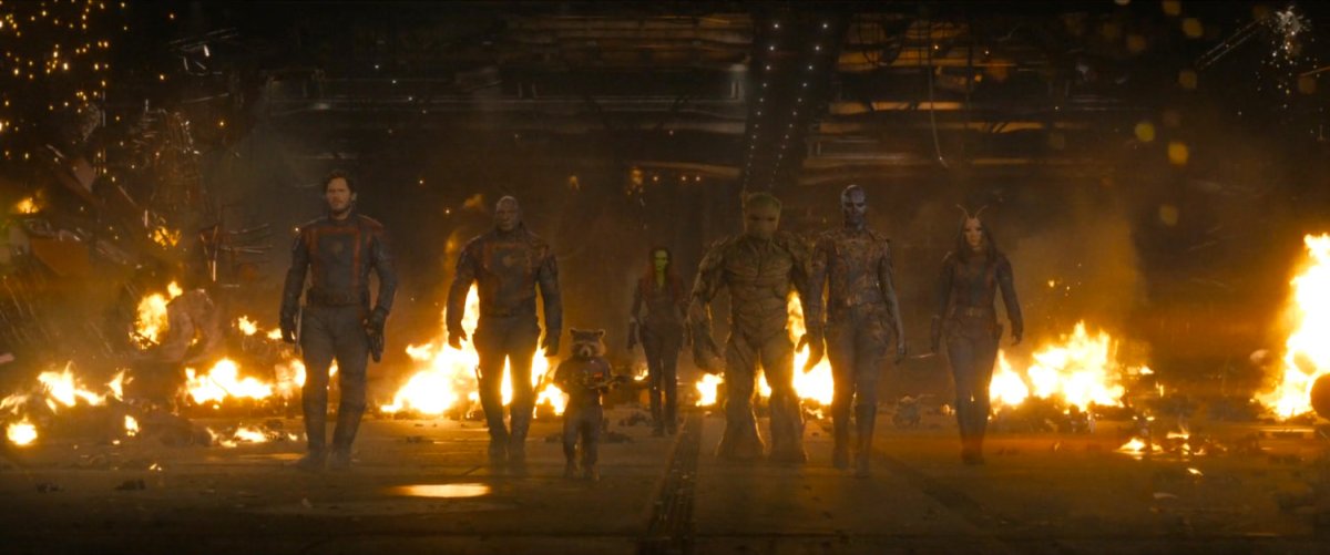 The Guardians of the Galaxy walk through a flaming hangar.