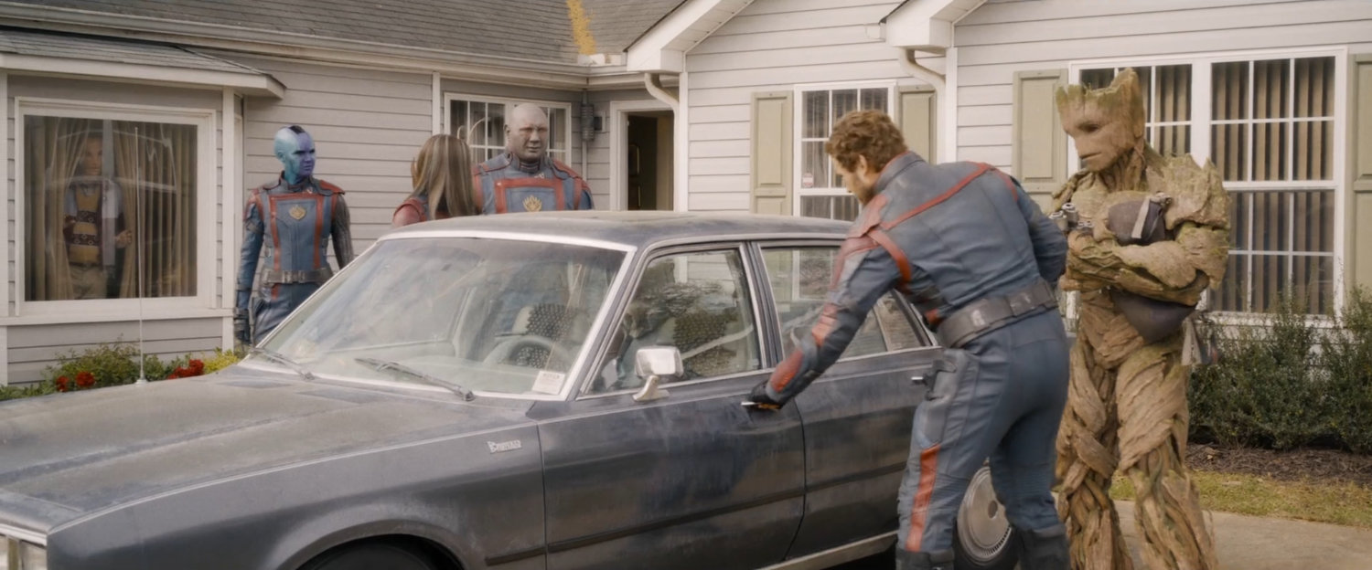 Star-Lord and Guardians get into a car outside a suburban home.