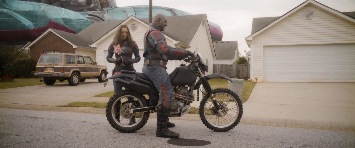Drax on a motorcycle, and Mantis, on a Counter-Earth suburban street.