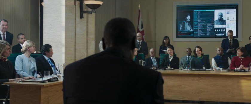 Colonel Rhodes facing a number of EU Leaders inside a small meeting chamber.